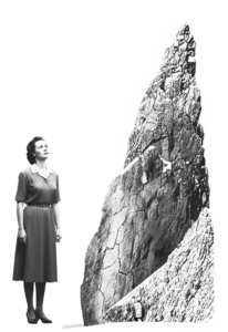 Frau steht vor einem Felsen und schaut hoch.